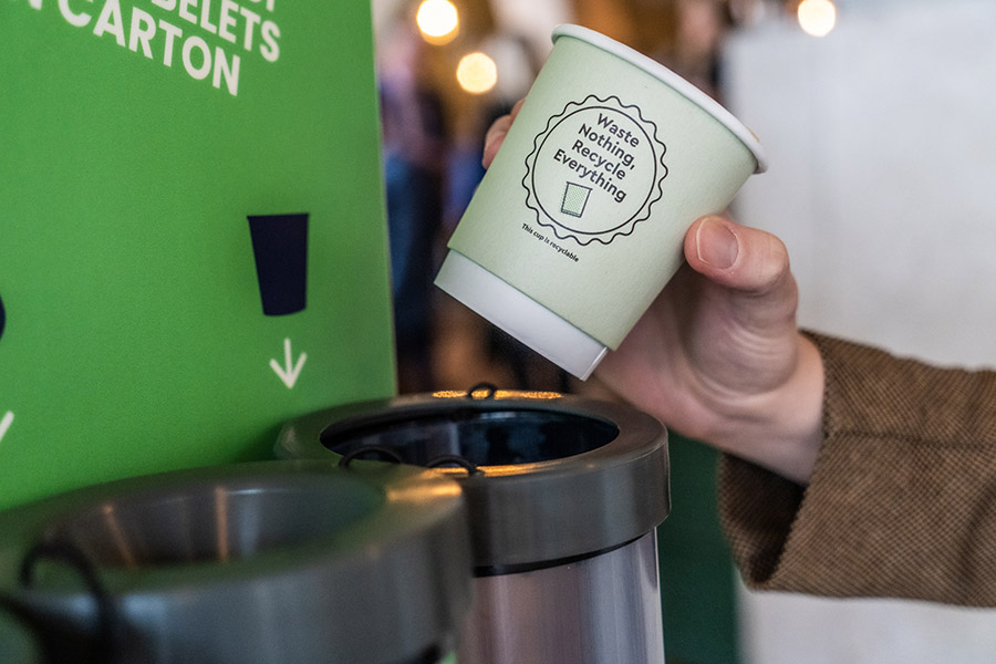 A used paper cup being placed into a dedicated Cup Collective collection bin