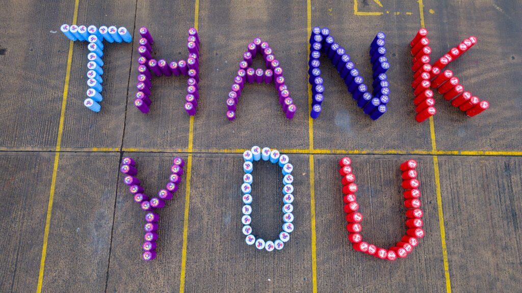 Collected tub lids arranged on the ground to spell out thank you